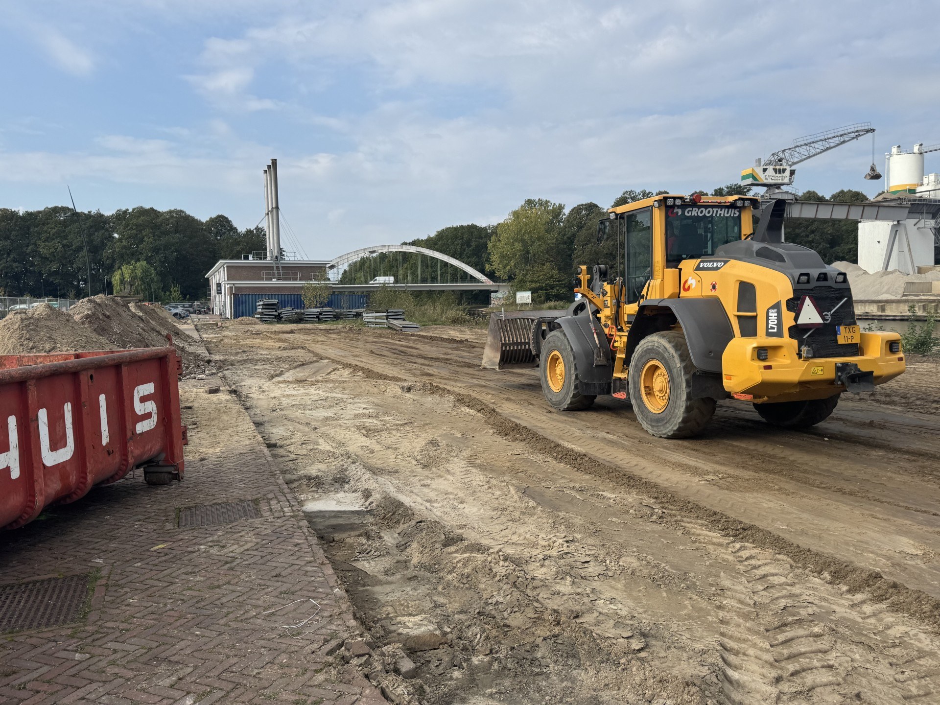 Grondwerk op de bouwlocatie van Gebouw Q met een gele wiellader en afgegraven terrein.
